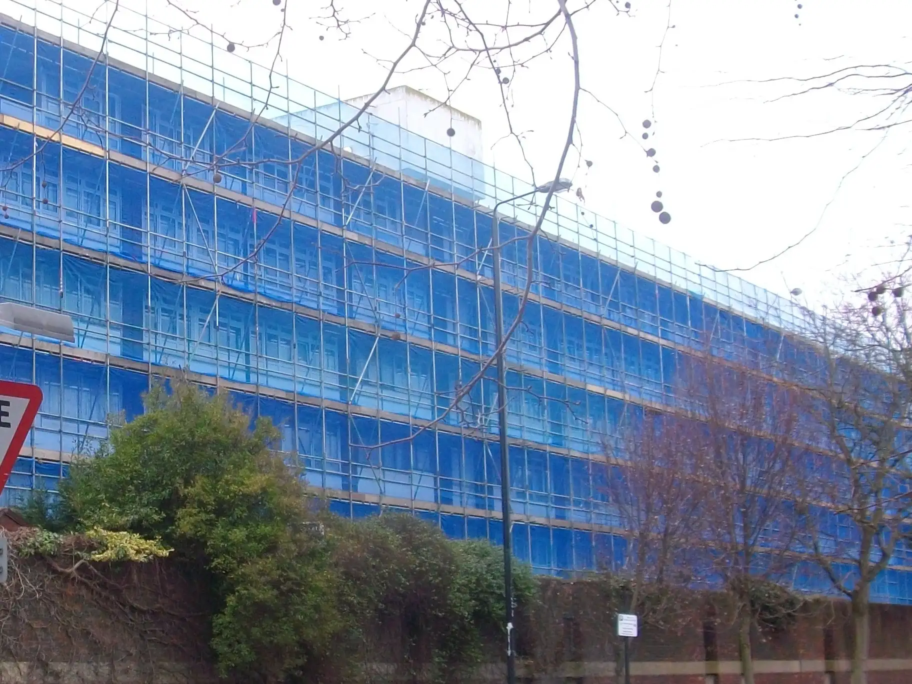Netted scaffold lifts along the elevation of a Basingstoke block during recladding