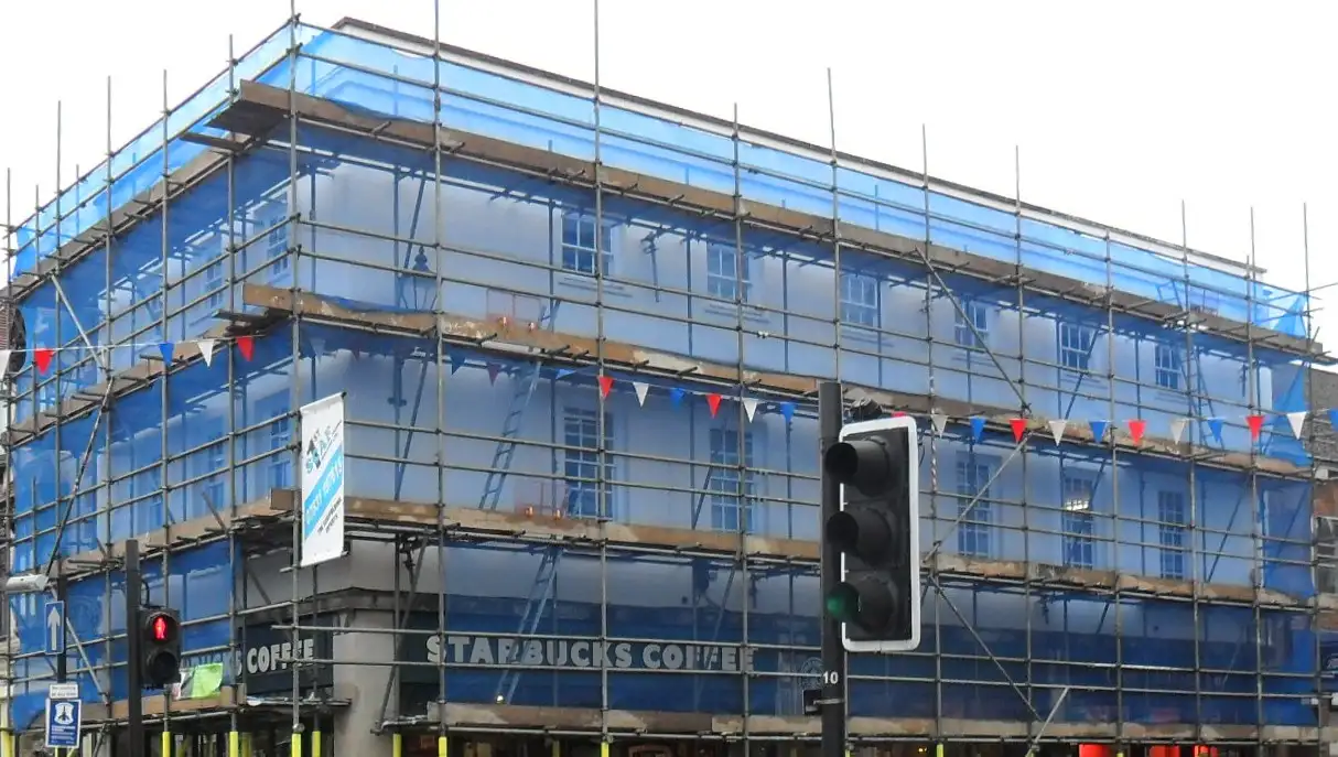 Netted upper lifts of a scaffold on a corner building on Henley high street
