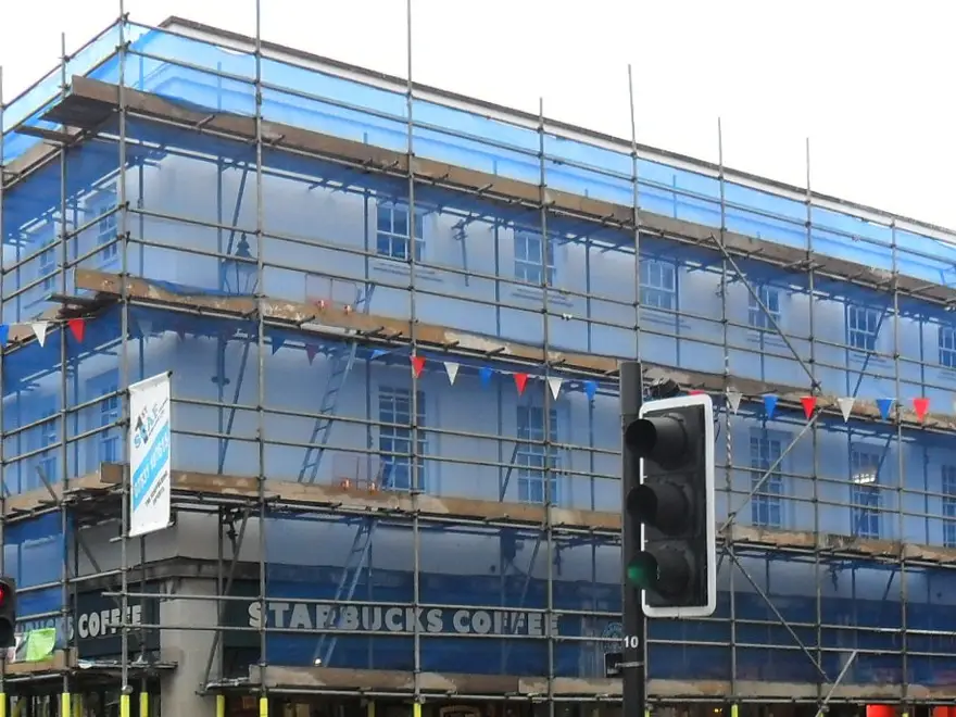 Netted upper lifts of a scaffold on a corner building on Henley high street