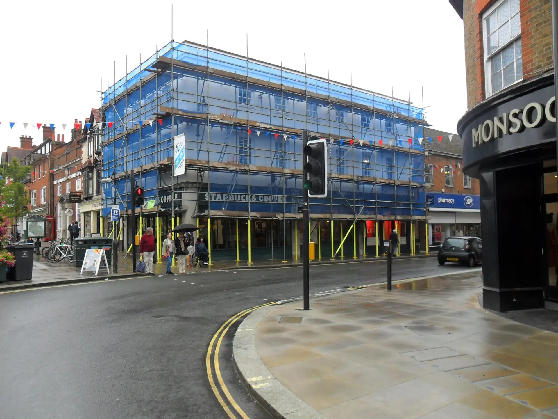 Netted scaffold on a corner building on Henley-on-Thames high street, with shops open below
