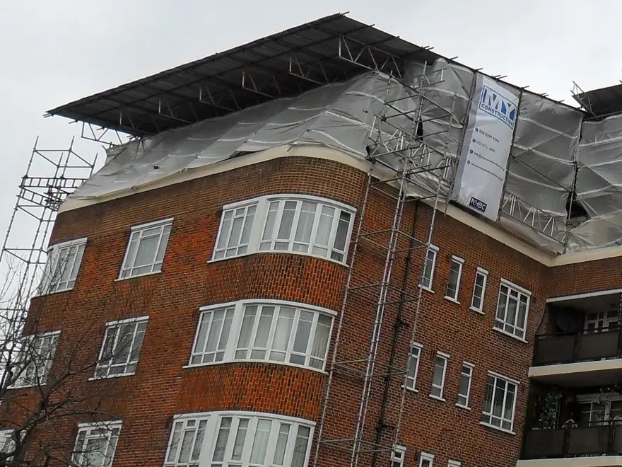 Scaffold access tower rising to a sheeted temporary roof on a High Wycombe apartment block