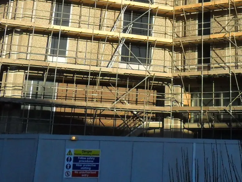 Site hoarding with safety signs at the base of the scaffold around Reading’s old council offices