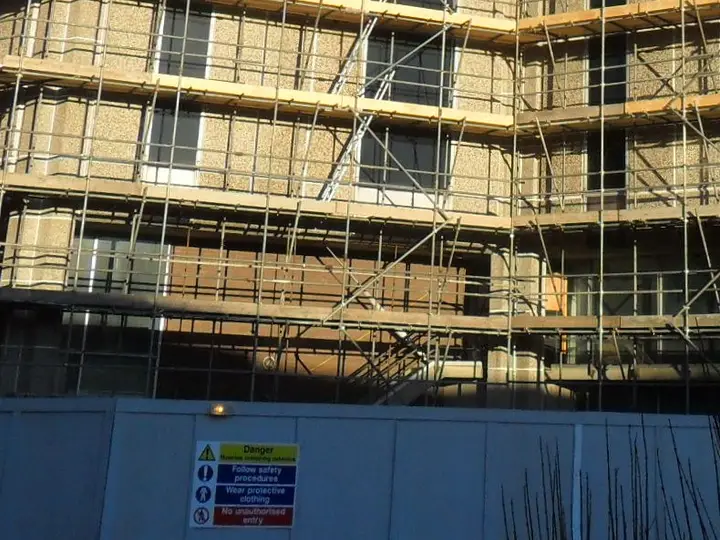 Site hoarding with safety signs at the base of the scaffold around Reading’s old council offices