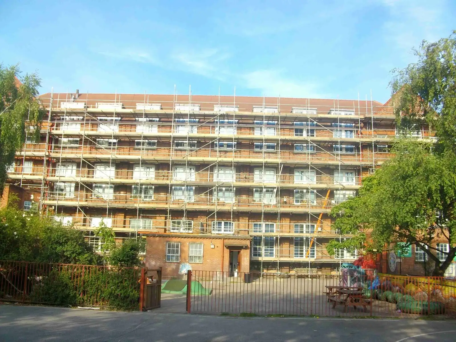 Scaffolding covering every elevation of a six-storey building under a blue sky
