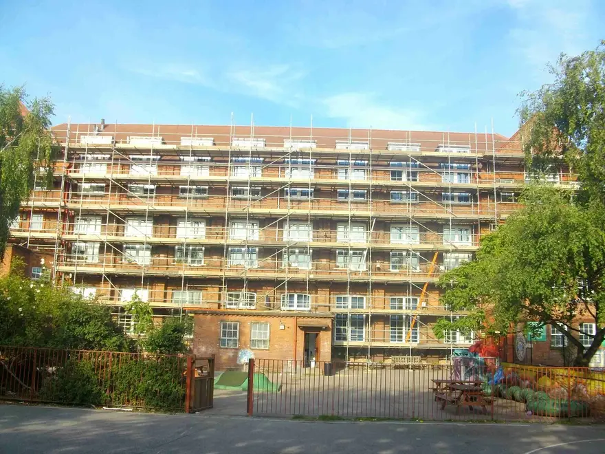 Scaffolding covering every elevation of a six-storey building under a blue sky